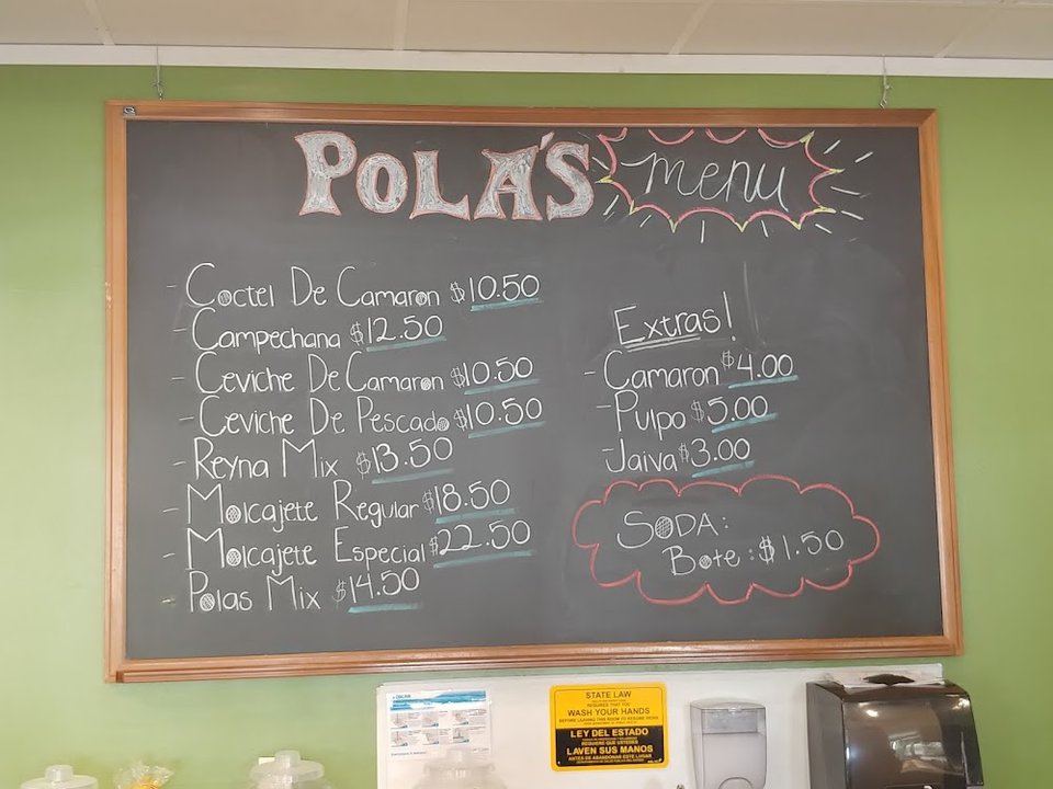 Menu board listing tacos, trays, and drinks.